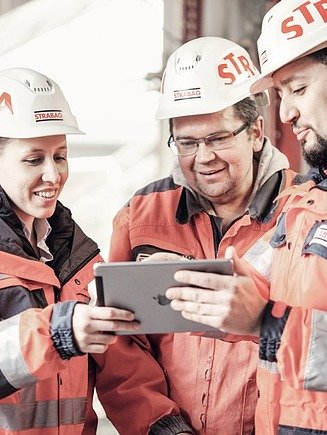 Photo: Three people wearing helmets are looking at a tablet
